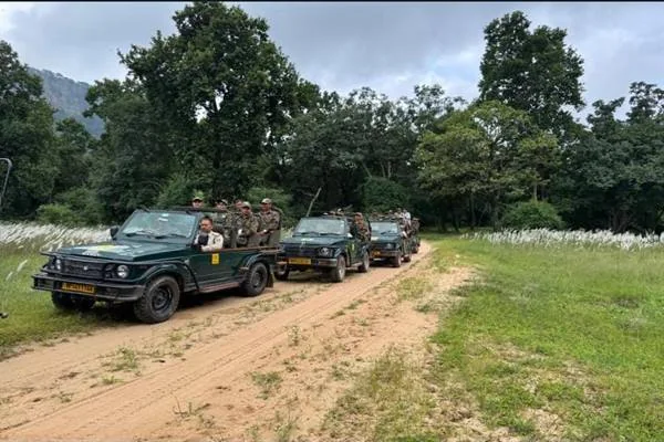 कच्चे जंगल मार्ग पर कतार में खड़े खुले सफारी वाहन और उनमें सवार वर्दीधारी लोग